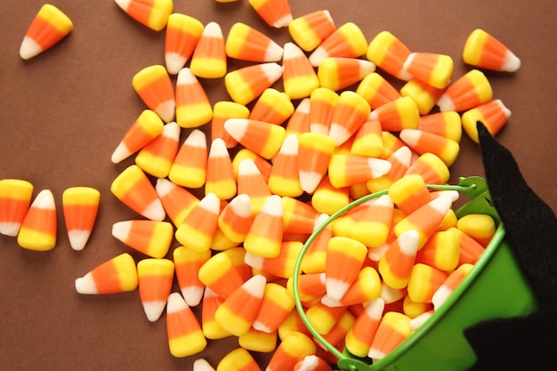 Seau et savoureux bonbons d'Halloween sur la surface de couleur