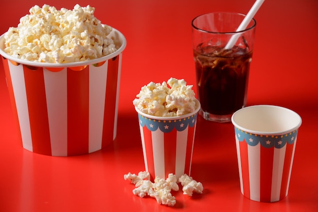 Seaux avec de délicieux pop-corn sur fond rouge et un verre de Coca-Cola