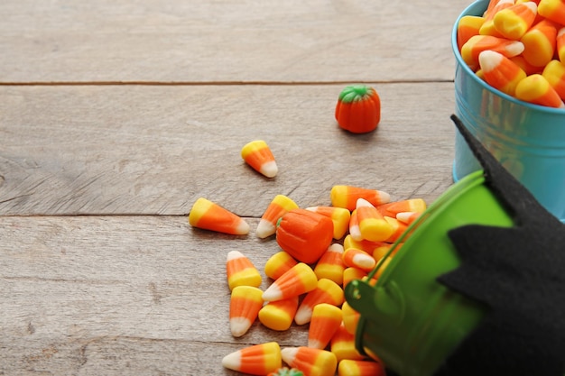 Seaux avec de savoureux bonbons d'Halloween sur fond de bois