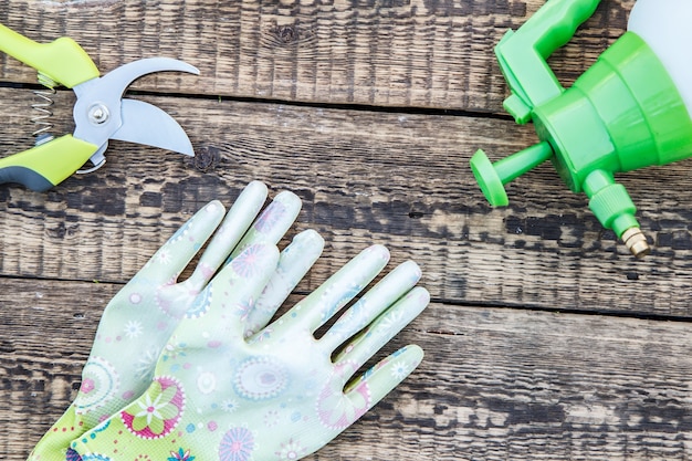 Sécateur, pulvérisateur à pression et gants de jardin sur planche de bois. Outils et équipement de jardin