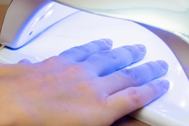 Séchage des ongles après application du vernis dans un séchoir spécial ultraviolet