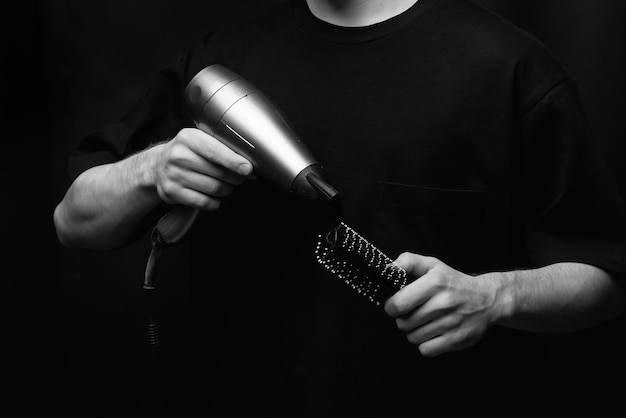 sèche-cheveux et peigne dans les mains du coiffeur