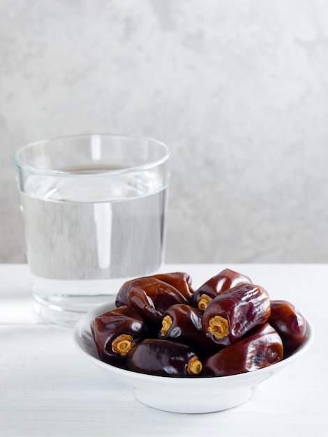 Sécher les dattes et un verre d&#39;eau sur une table blanche - Ramadan, nourriture d&#39;Iftar.