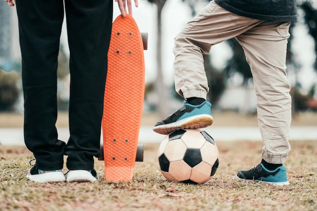 Photo section basse d'amis avec skateboard et balle de football sur le terrain