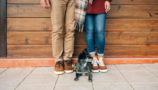 Section basse du couple avec chien debout devant un mur en bois