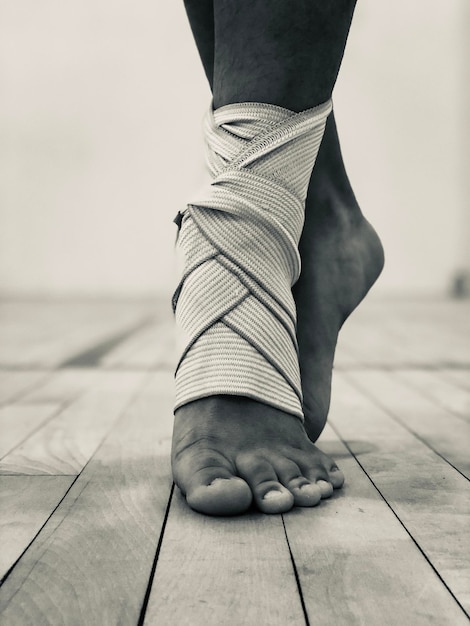 Photo section basse d'une femme avec un bandage dansant sur le sol en bois dur