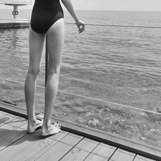 Section basse d'une femme debout sur une jetée au bord de la mer