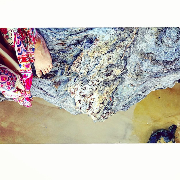 Photo section basse d'une femme sur un rocher à la plage
