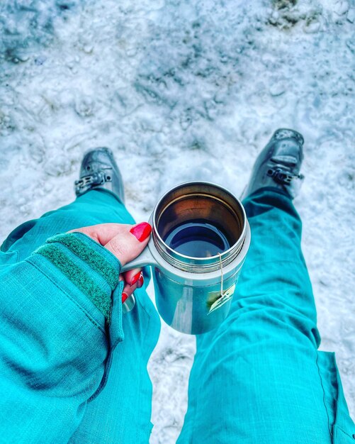 Photo section basse d'une femme tenant du café dans une station de ski