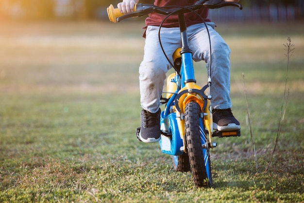 Photo section basse d'un garçon qui fait du vélo sur l'herbe