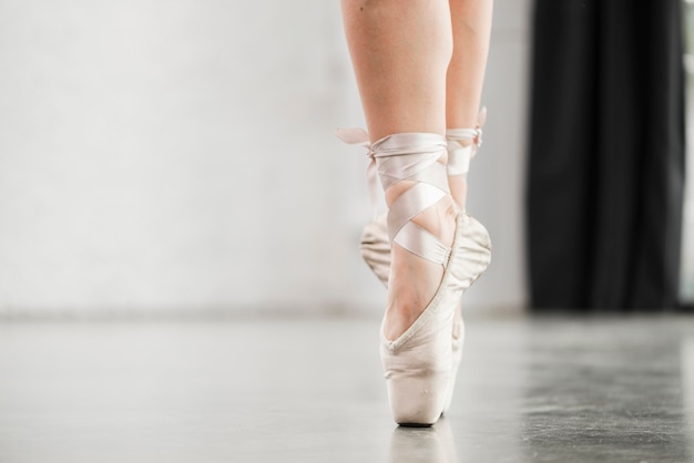 Section basse de la jambe de la ballerine dans les chaussures de pointe debout sur le sol