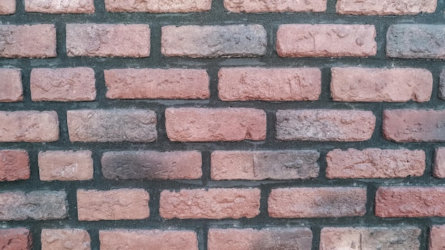 Une section horizontale d'un vieux mur de briques peint en noir et rouge