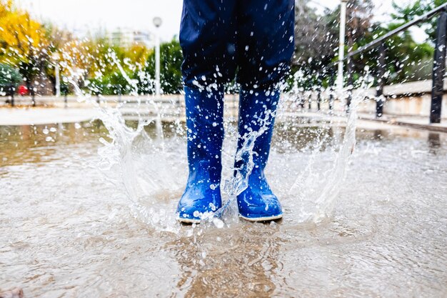 Section inférieure de l'enfant éclaboussant de l'eau sous la pluie