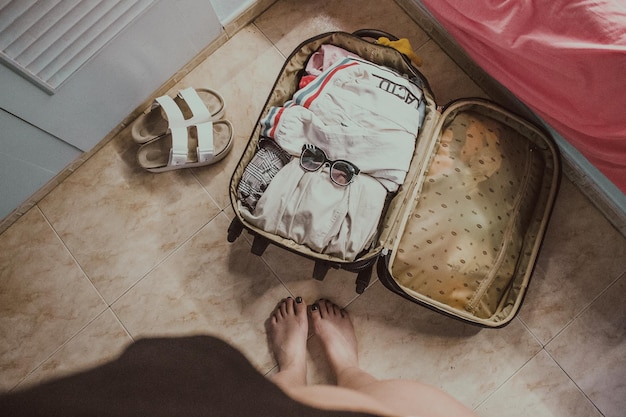 Section inférieure de la femme debout par les bagages à la maison