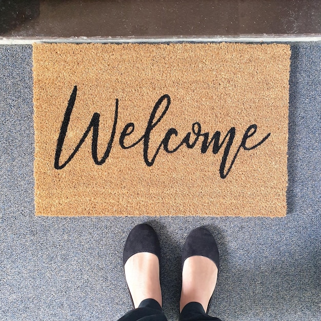 Section inférieure de la femme debout sur le tapis d'accueil