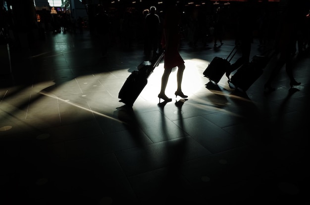 Section inférieure d'une femme marchant avec des bagages à l'aéroport