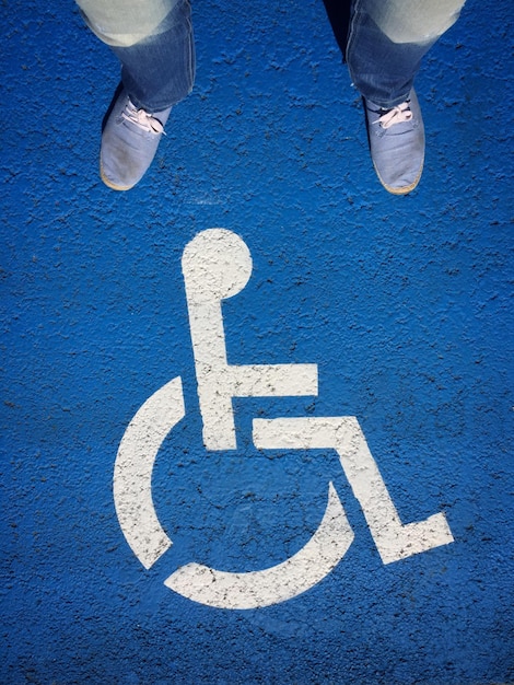 Section inférieure de l'homme debout sur un panneau pour personnes handicapées