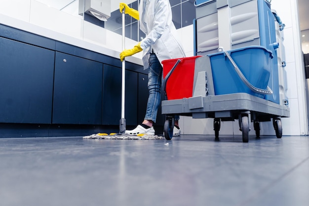 Section inférieure de l'homme nettoyant le sol dans les toilettes publiques