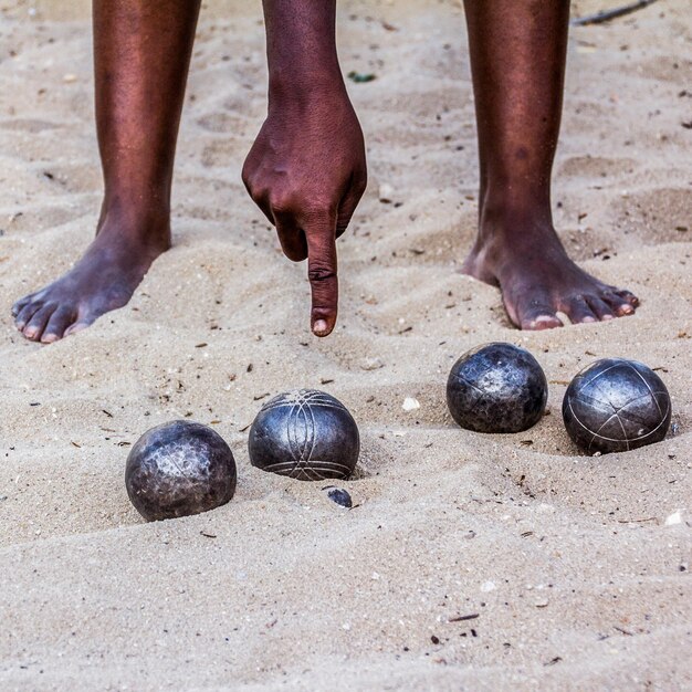 Photo section inférieure de l'homme pointant des balles sur le sable