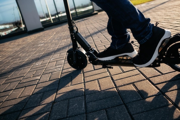 Section inférieure de l'homme sur le scooter à poussée