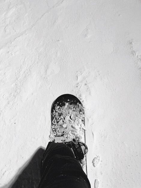 Photo section inférieure d'une personne faisant du snowboard sur le terrain