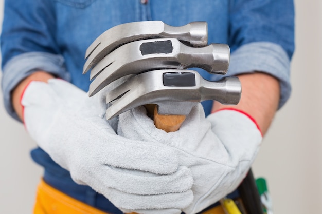 Section médiane d&#39;un bricoleur tenant des marteaux avec une ceinture d&#39;outil autour de la taille