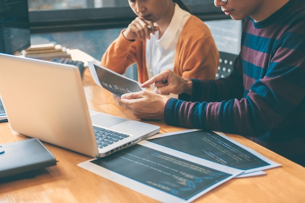 Une section médiane de codeurs travaillant assis sur une table au bureau.