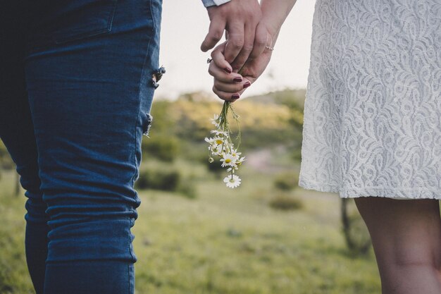 Section médiane d'un couple se tenant par la main et des fleurs