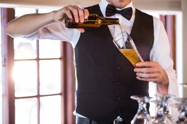 Section médiane du barman versant une bière dans un verre