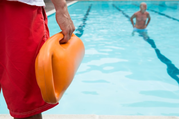 Section médiane du sauveteur tenant la bouée de sauvetage au bord de la piscine