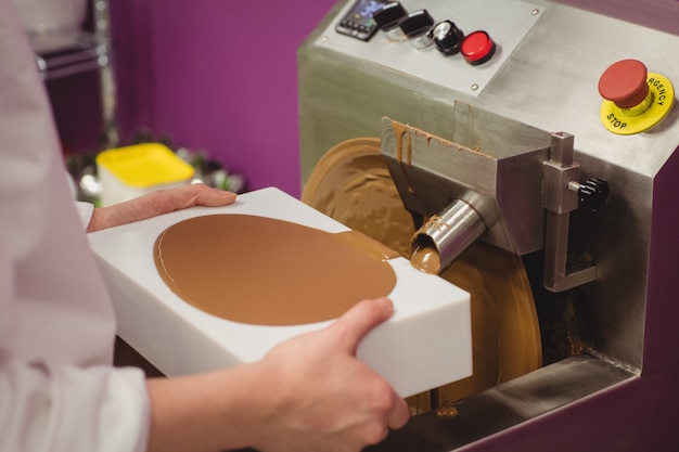 Section médiane du travailleur remplissant le moule de chocolat fondu