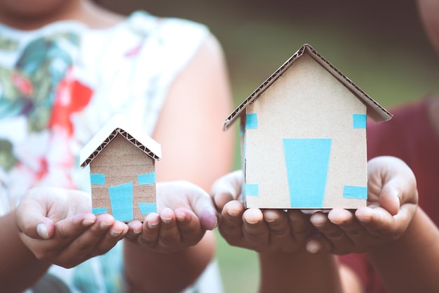 Section médiane d'enfants tenant une maison en carton alors qu'ils se tiennent à l'extérieur