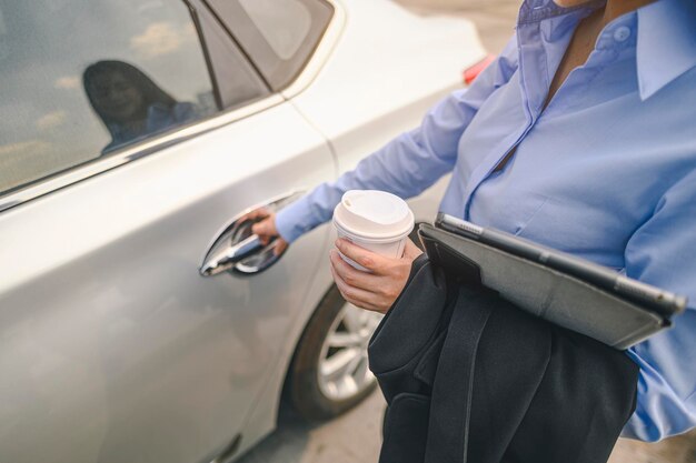 Section médiane d'une femme d'affaires tenant du café alors qu'elle se tient près de la voiture