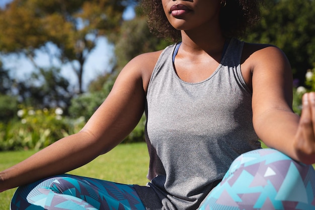 Section médiane d'une femme afro-américaine pratiquant le yoga dans un jardin ensoleillé. mode de vie actif, fitness en plein air et loisirs.