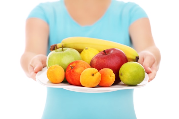 Une section médiane d'une femme avec une assiette de fruits sur fond blanc