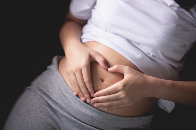 Section médiane d'une femme donnant une forme de cœur sur le ventre de la femme enceinte
