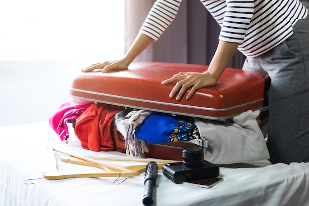 Photo section médiane d'une femme emballant une valise sur le lit dans une chambre d'hôtel