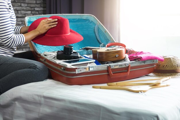 Photo section médiane d'une femme emballant une valise sur le lit à la maison