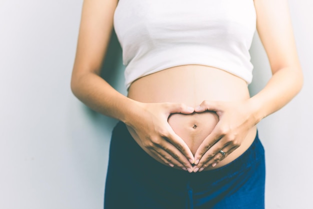 Section médiane d'une femme enceinte en forme de cœur sur l'estomac sur un fond blanc