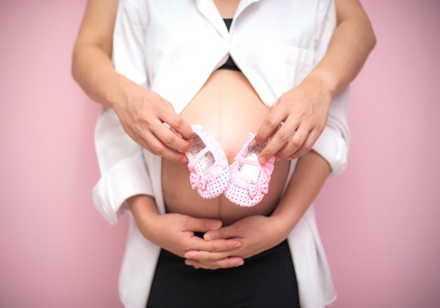 Section médiane d'une femme enceinte avec un homme tenant des bottes de bébé