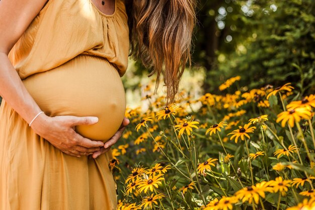 Section médiane d'une femme enceinte tenant l'estomac alors qu'elle se tient à l'extérieur