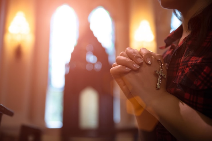Photo section médiane d'une femme avec les mains serrées priant dans l'église