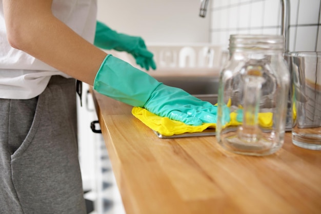 Section médiane d'une femme nettoyant le comptoir de la cuisine à la maison