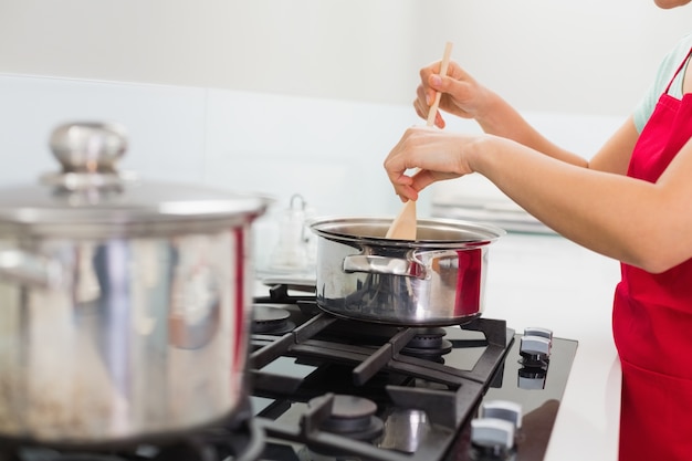 Section médiane d&#39;une femme préparant la nourriture dans la cuisine