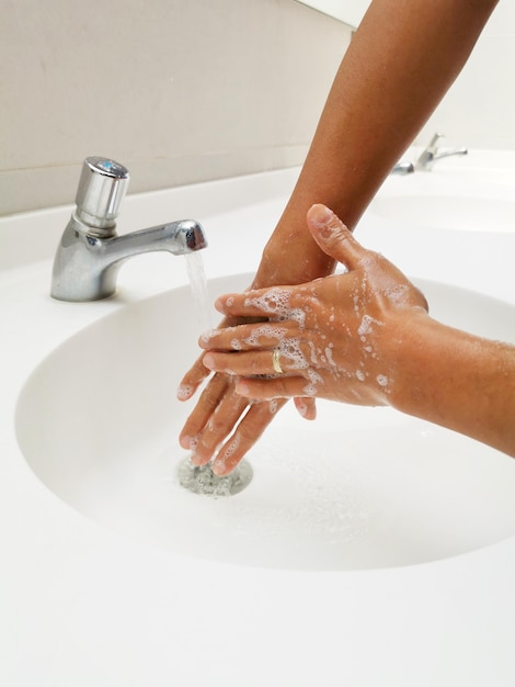 Photo section médiane d'une femme avec un robinet dans la salle de bain