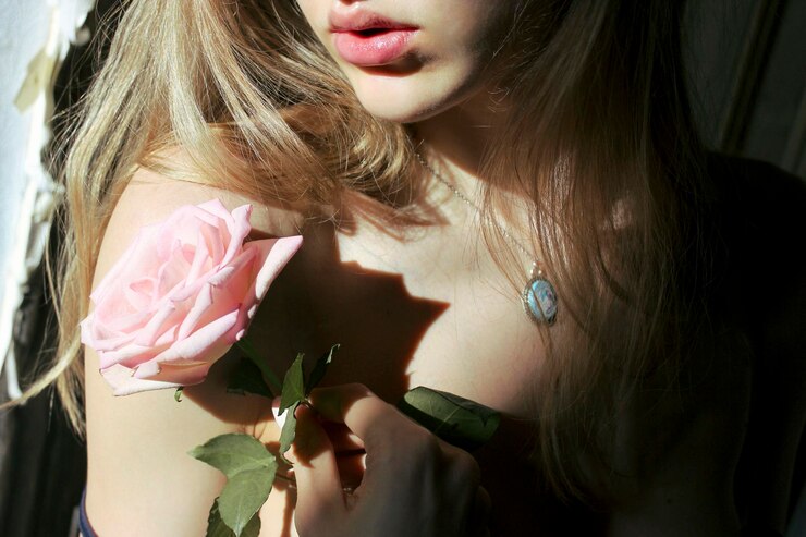Photo section médiane d'une femme avec une rose rose par une journée ensoleillée