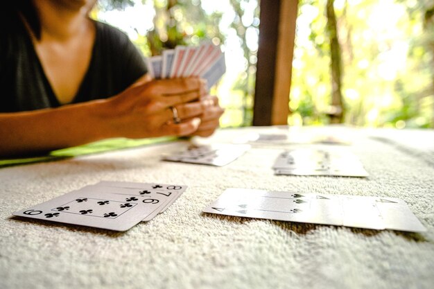 Section médiane d'une femme tenant une carte de jeu sur la table