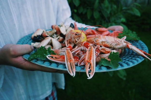 Section médiane d'une femme tenant des fruits de mer dans une assiette