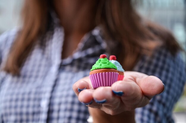 Section médiane d'une femme tenant de petits gâteaux sur la paume