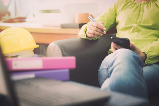 Section médiane d'une femme utilisant une carte et un téléphone portable sur le canapé